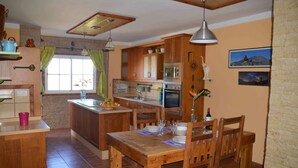 A kitchen with wooden cabinets, a dining table, and a window with curtains.