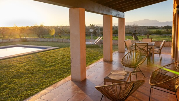 Un patio techado con piscina, mobiliario exterior y vista al paisaje.