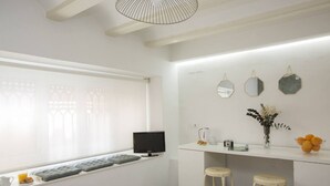 A bright, modern kitchen with a large window, a built-in TV, bar stools, and a countertop with a vase of flowers and oranges. - Singular Stays Botanico Room IV (Valencia ciudad)
