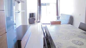 Een slaapkamer met een bed, een televisie, een dressoir en een raam met gordijnen.