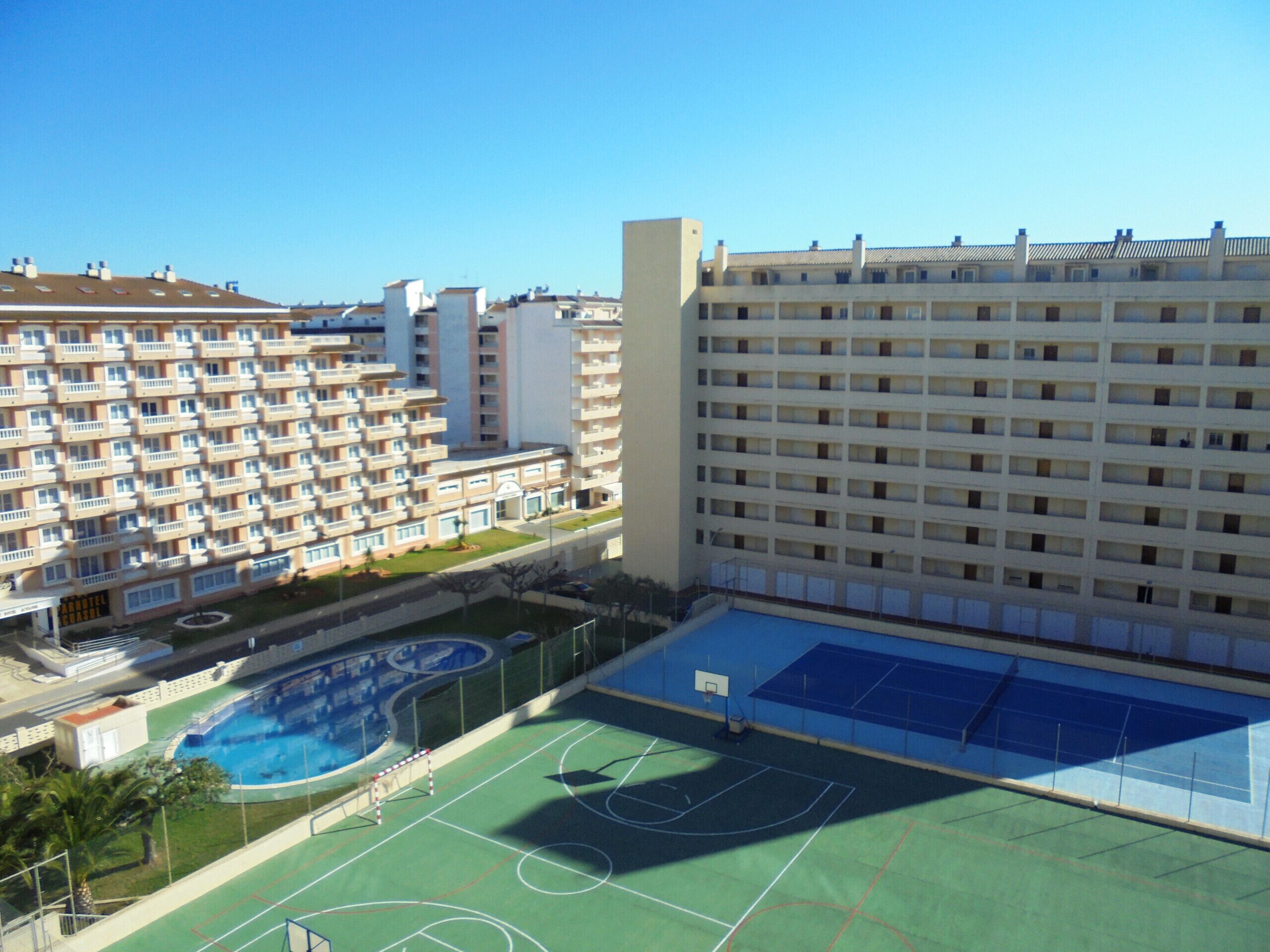 A multi-story hotel with a rooftop pool and tennis court.