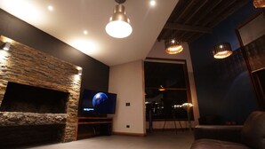 Un salon moderne avec une cheminée en pierre, un téléviseur à écran plat et une grande fenêtre.