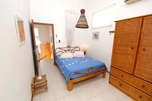 A bedroom with a bed, wooden wardrobe, and a hanging light fixture.