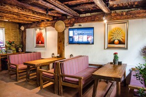 A rustic interior with wooden furniture, a television mounted on the wall, and framed artwork. - Shangri-La E-Outfitting Boutique Hotel (Deqin)