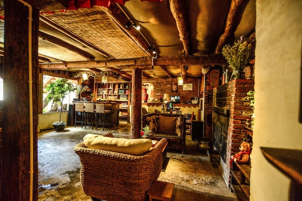 Un intérieur chaleureux et rustique, avec un fauteuil en osier, une cheminée en briques et un coin bar.