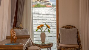 A room with a view of a traditional building, a vase with flowers, and wicker chairs. - Shangri-La E-Outfitting Boutique Hotel (Deqin)