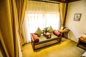A cozy room with a wooden sofa, a small table, and a vase with flowers. - Shangri-La E-Outfitting Boutique Hotel (Deqin)
