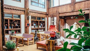 A cozy, well-lit room with wooden furniture, bookshelves, and a central table with chairs. - Shangri-La E-Outfitting Boutique Hotel (Deqin)