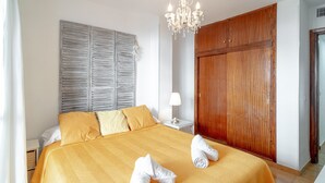 Habitación de hotel con una cama grande, armario de madera y una araña.