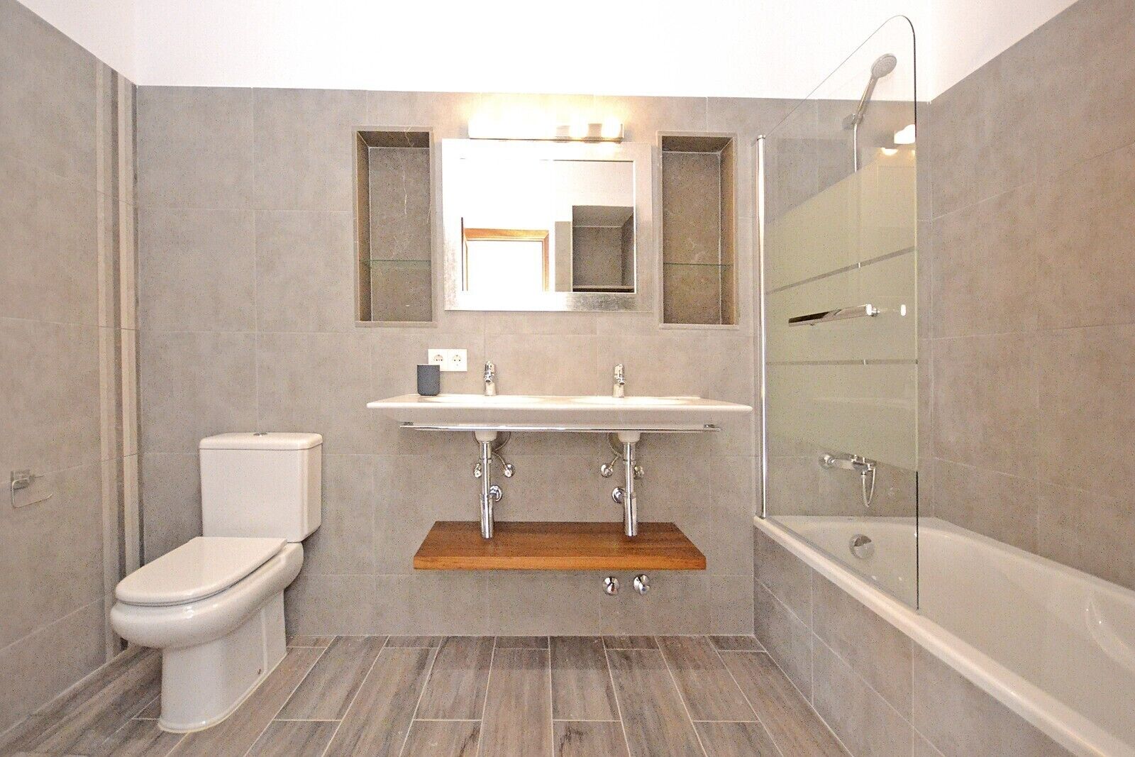 Un baño moderno con inodoro, lavamanos y ducha.