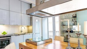 Eine moderne Küche mit Esstisch mit Glasplatte, Edelstahlgeräten und einer Vitrine mit Glastür.