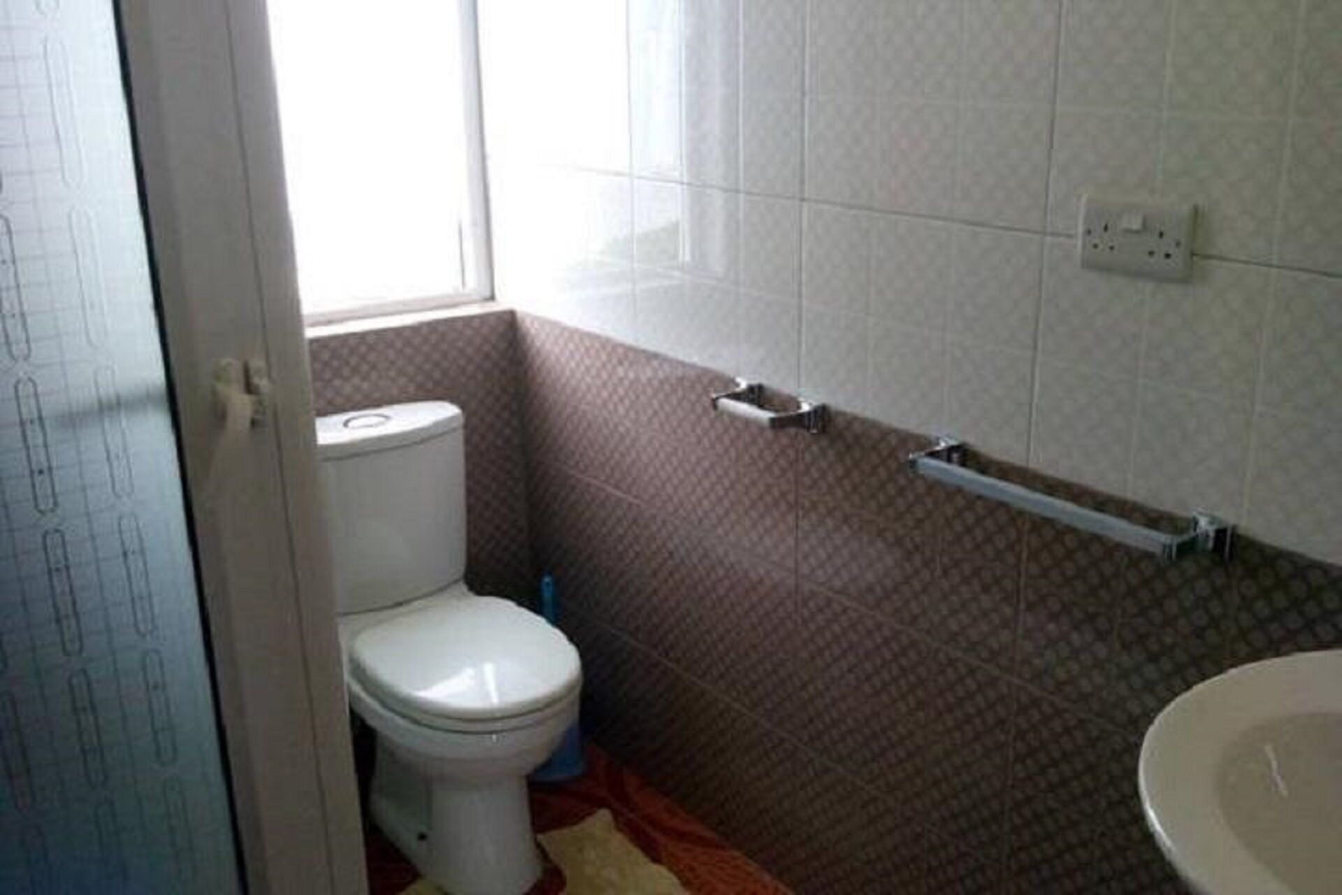 A bathroom with a toilet, a towel rack, and a sink.