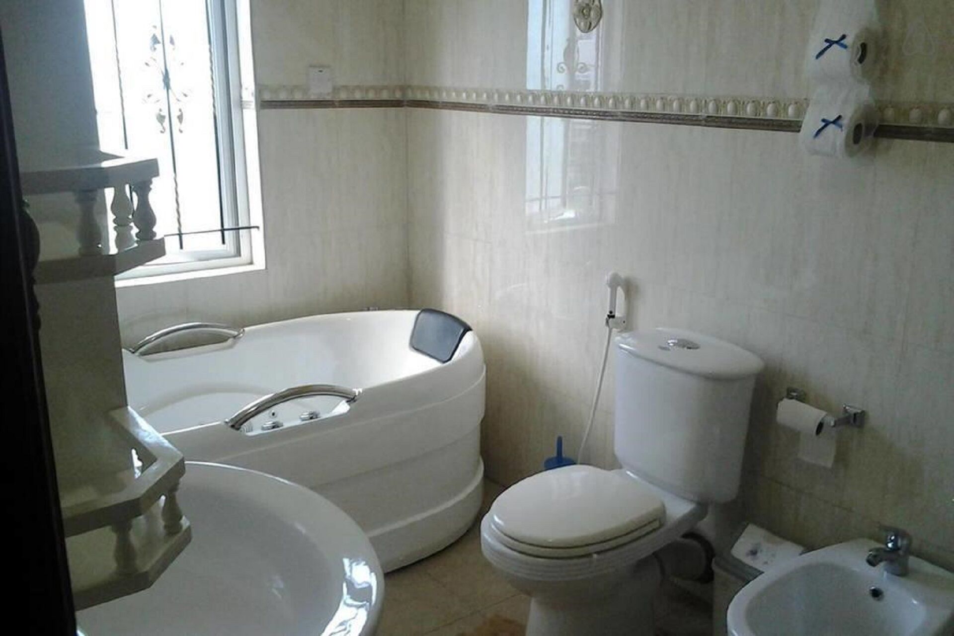 A bathroom with a bathtub, toilet, sink, and bidet.
