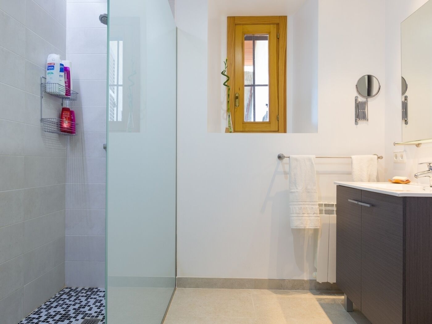 Ein modernes Badezimmer mit Dusche, Waschtisch und Spiegel sowie einem Fenster.