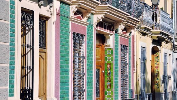 A building with ornate architectural details, including decorative metalwork on the windows and doors, and a patterned facade.