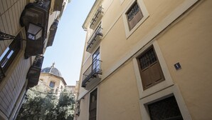 A narrow street with buildings, a dome structure in the background, and a sign indicating a location. - Singular Stays El Micalet (Valencia)