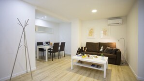A modern living room with a white coffee table, a brown sofa, and a dining area with a white table and chairs. - Singular Stays El Micalet (Valencia)