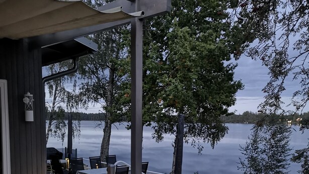 Une terrasse en bois, aménagée avec du mobilier d’extérieur, donnant sur un lac.