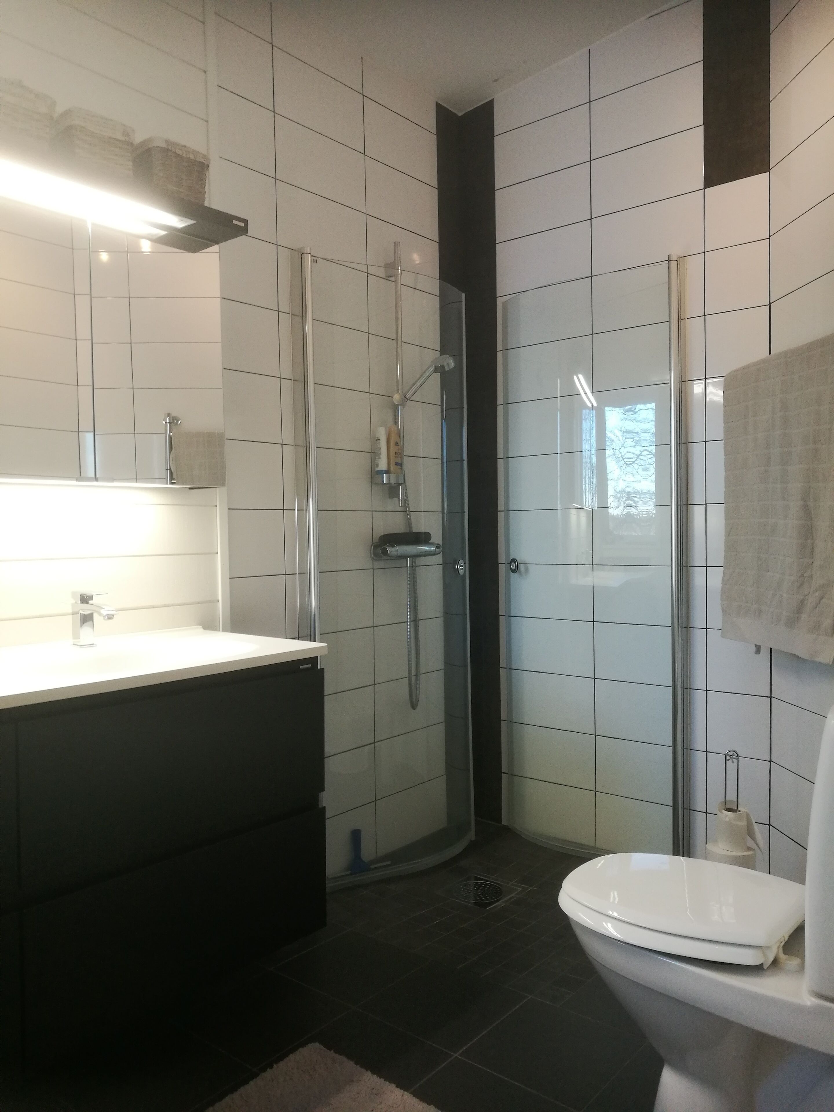 Un baño moderno con un lavamanos blanco, inodoro y cabina de ducha con mampara de vidrio.