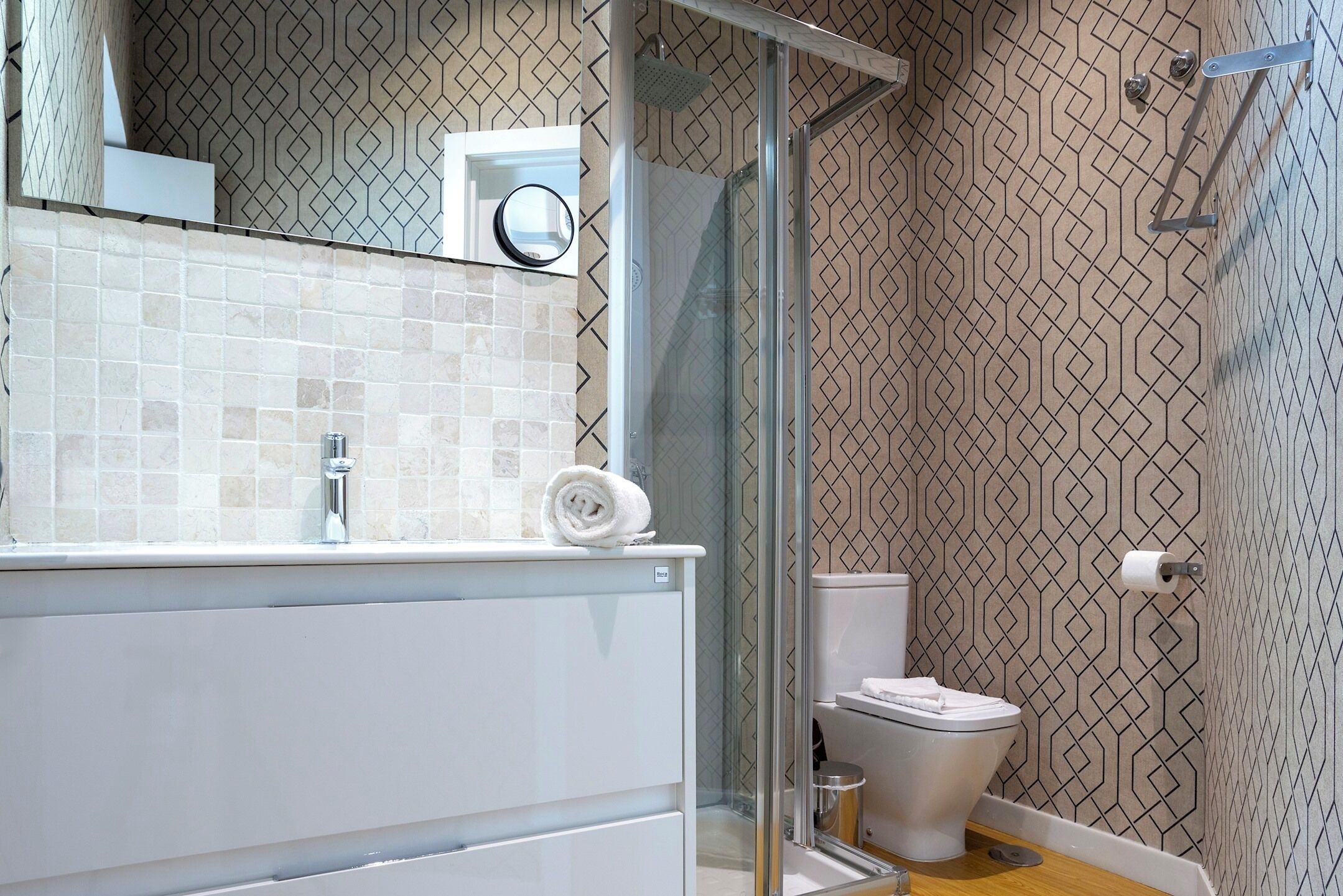 A bathroom with a glass shower enclosure, a toilet, and a sink with a towel on the counter.