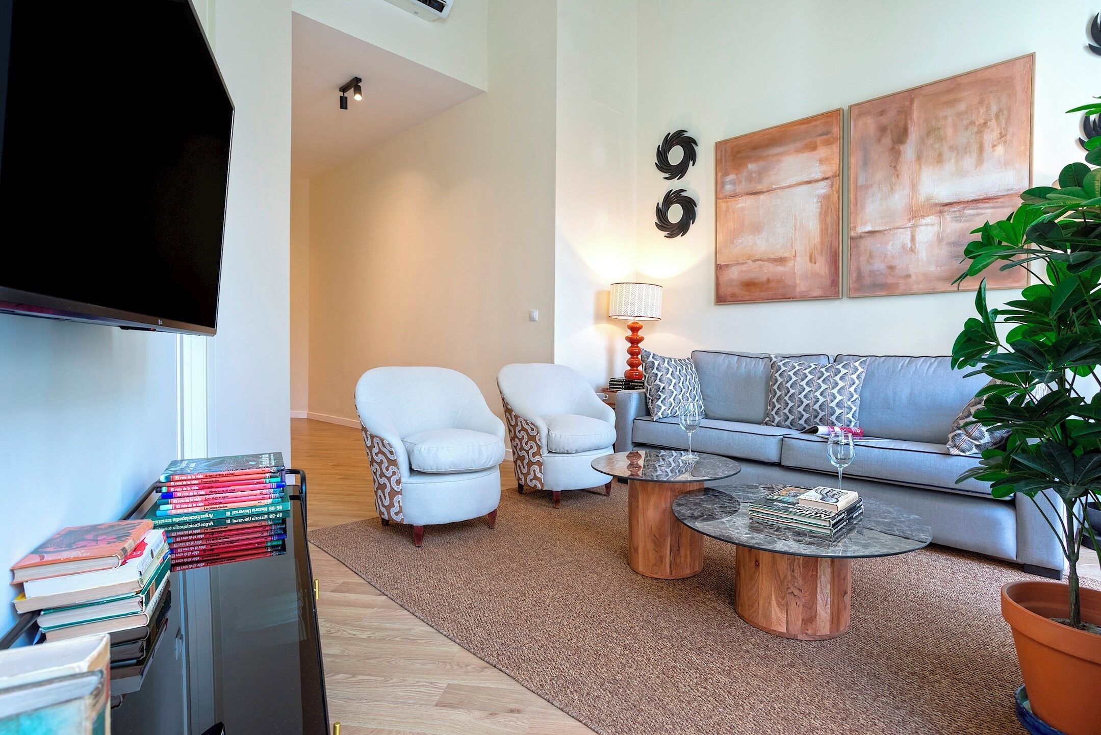 A living room with a sofa, two armchairs, a coffee table, a TV, and a bookshelf.