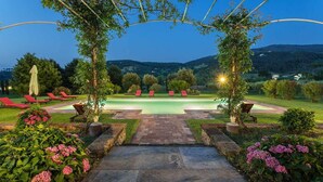 A pool area with lounge chairs, a stone pathway, and a view of the hills. - Casa del Fattore   . (Capannori)