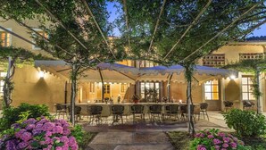 A covered outdoor bar area with seating, surrounded by greenery and a stone pathway. - Casa del Fattore   . (Capannori)