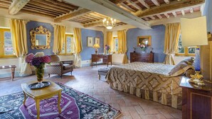 A bedroom with a large bed, a desk, a chair, a vanity with a mirror, and a chandelier. - Casa del Fattore   . (Capannori)