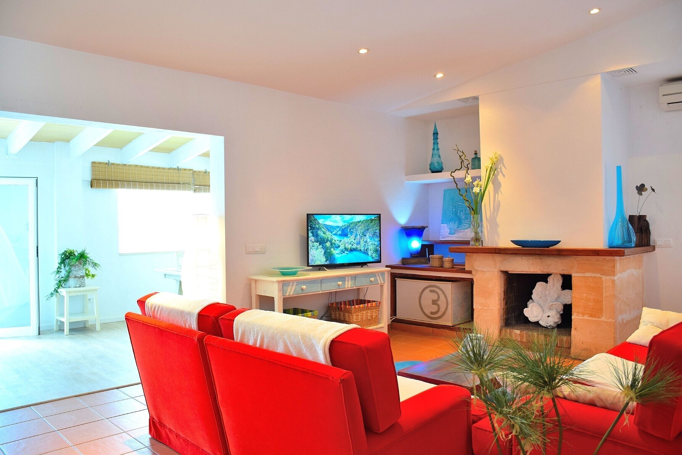 Una sala de estar moderna con un sofá rojo, un televisor y una chimenea.