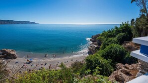 Une plage à l’eau d’un bleu cristallin, bordée de falaises rocheuses et d’une végétation luxuriante.