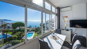 Une chambre d’hôtel dotée d’une grande fenêtre donnant sur la mer et une piscine.