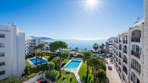 Un complexe hôtelier doté d’une piscine, de palmiers et offrant une vue sur la mer.