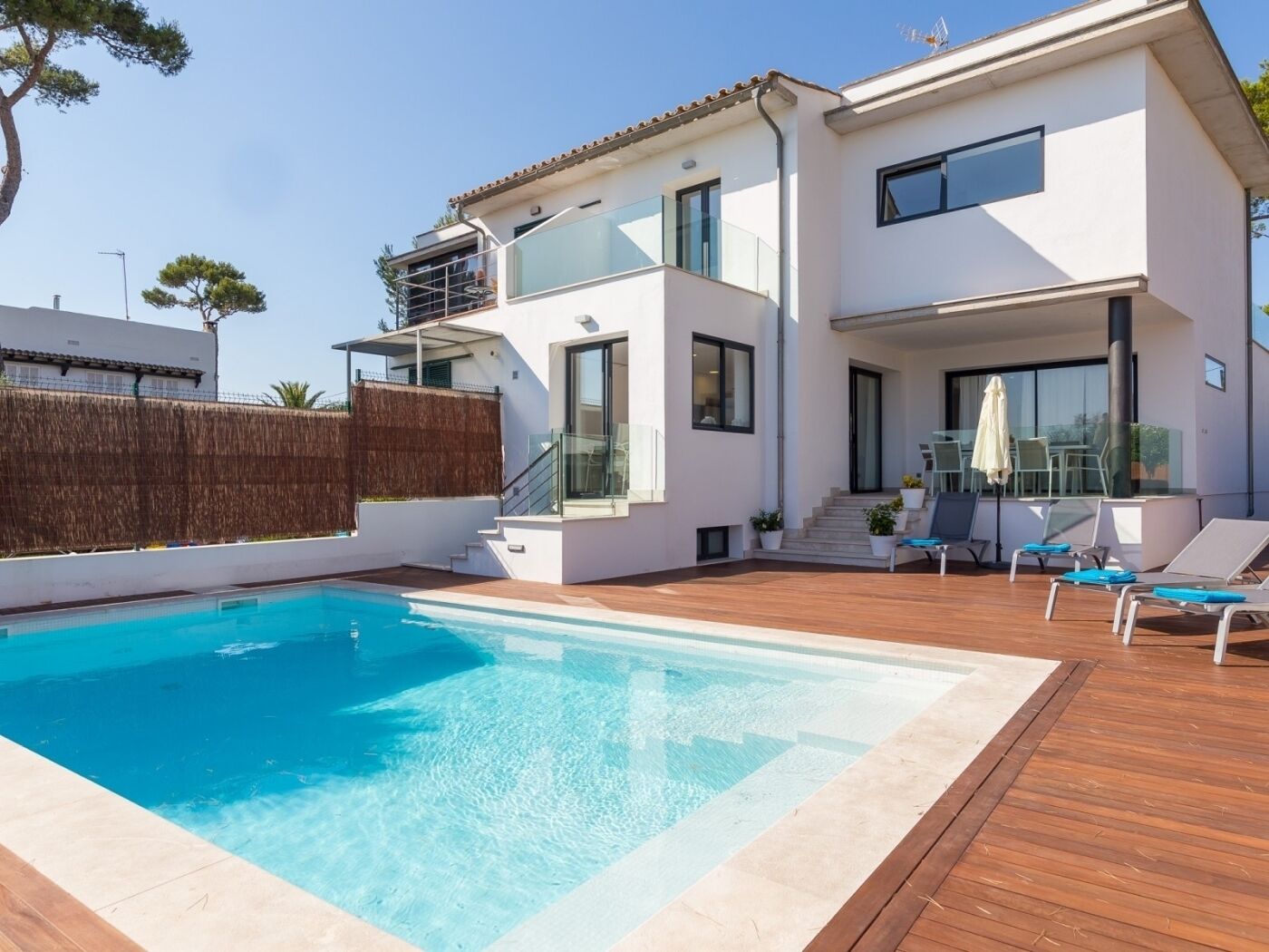 A modern two-story house with a swimming pool, outdoor seating, and a staircase leading to the upper floor.