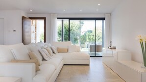 Een moderne woonkamer met een grote hoekbank, een glazen deur die leidt naar een balkon, en een minimalistisch design.