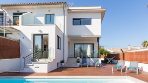 Een modern huis met twee verdiepingen, een zwembad, terras en een trap naar de bovenverdieping.