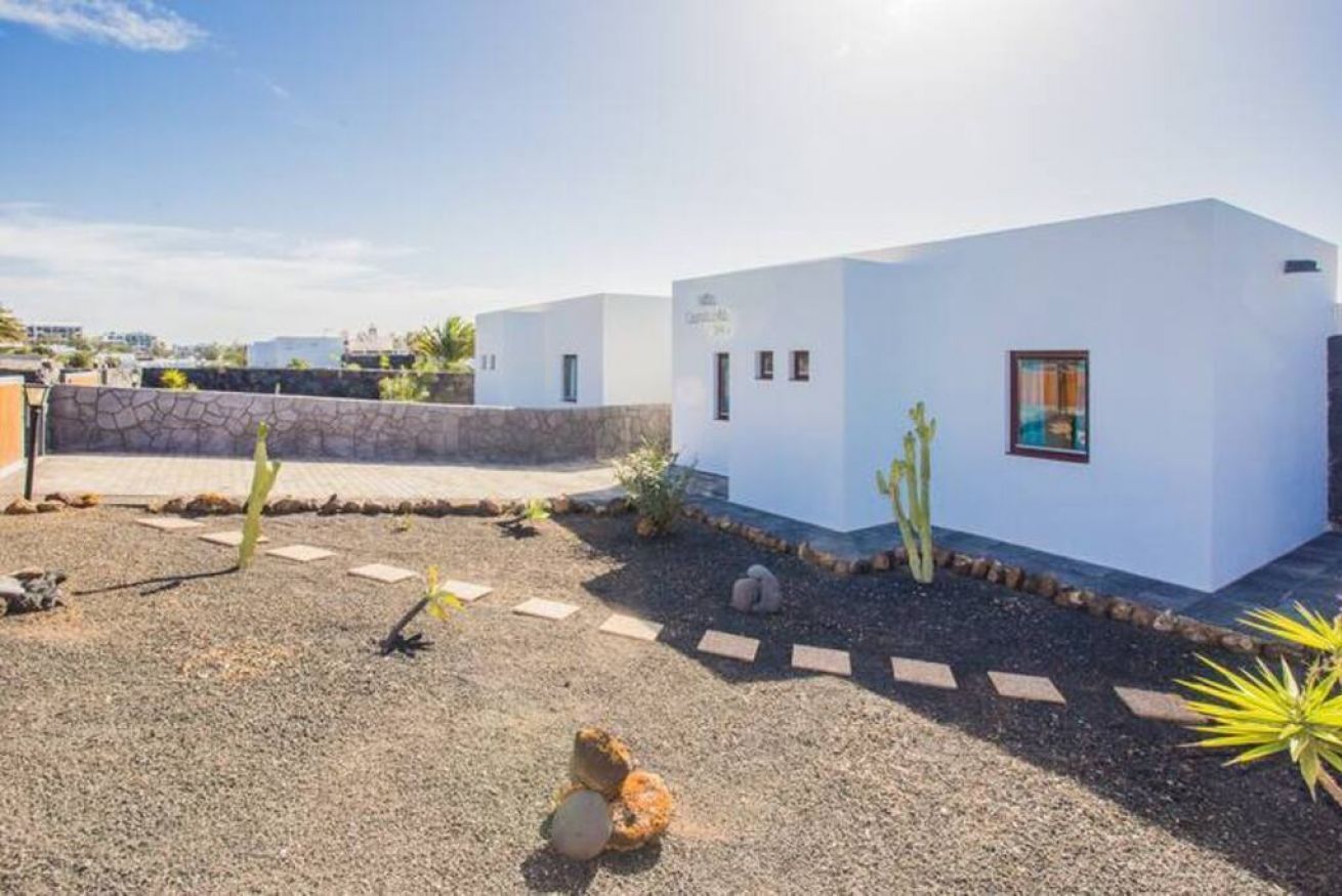 Un bâtiment moderne de couleur blanche, doté d’un petit jardin agrémenté de cactus et de rochers.