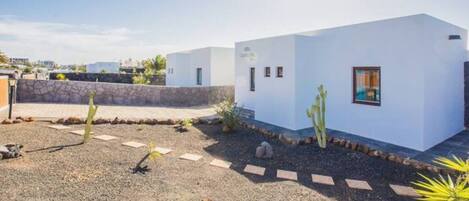 Un bâtiment moderne de couleur blanche, doté d’un petit jardin agrémenté de cactus et de rochers.