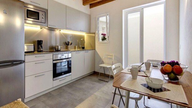 A modern kitchen with stainless steel appliances, a wooden ceiling, and a dining area with a table set for two.