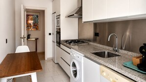 A compact kitchen with a washing machine, a stove, and a sink.
