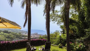 A patio with two chairs and a table, overlooking a scenic view of a town and the sea. - Apartment on the Amalfi Coast PARKING SPACE AND POOL (Salerno)