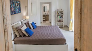 A bedroom with a bed, a bookshelf, and a bathroom visible through an open door. - Apartment on the Amalfi Coast PARKING SPACE AND POOL (Salerno)