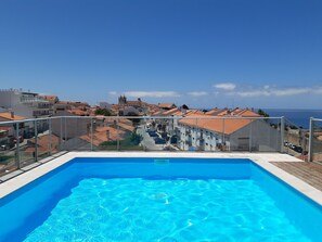 Une piscine sur le toit offrant une vue dégagée sur les bâtiments environnants et la mer.