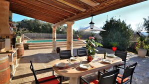 An outdoor dining area with a wooden pergola, a pool in the background, and potted plants. - Sa Rota 078 fantastic finca with private pool, garden, ping pong and fibre optics (Ariany)