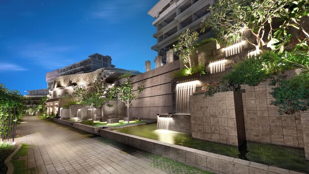 A nighttime view of a modern building with a water feature, stone walls, and greenery. - The Sterling Villas (Pecatu)