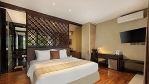 A hotel room with a large bed, a TV, a desk, and a decorative partition. - The Sterling Villas (Pecatu)