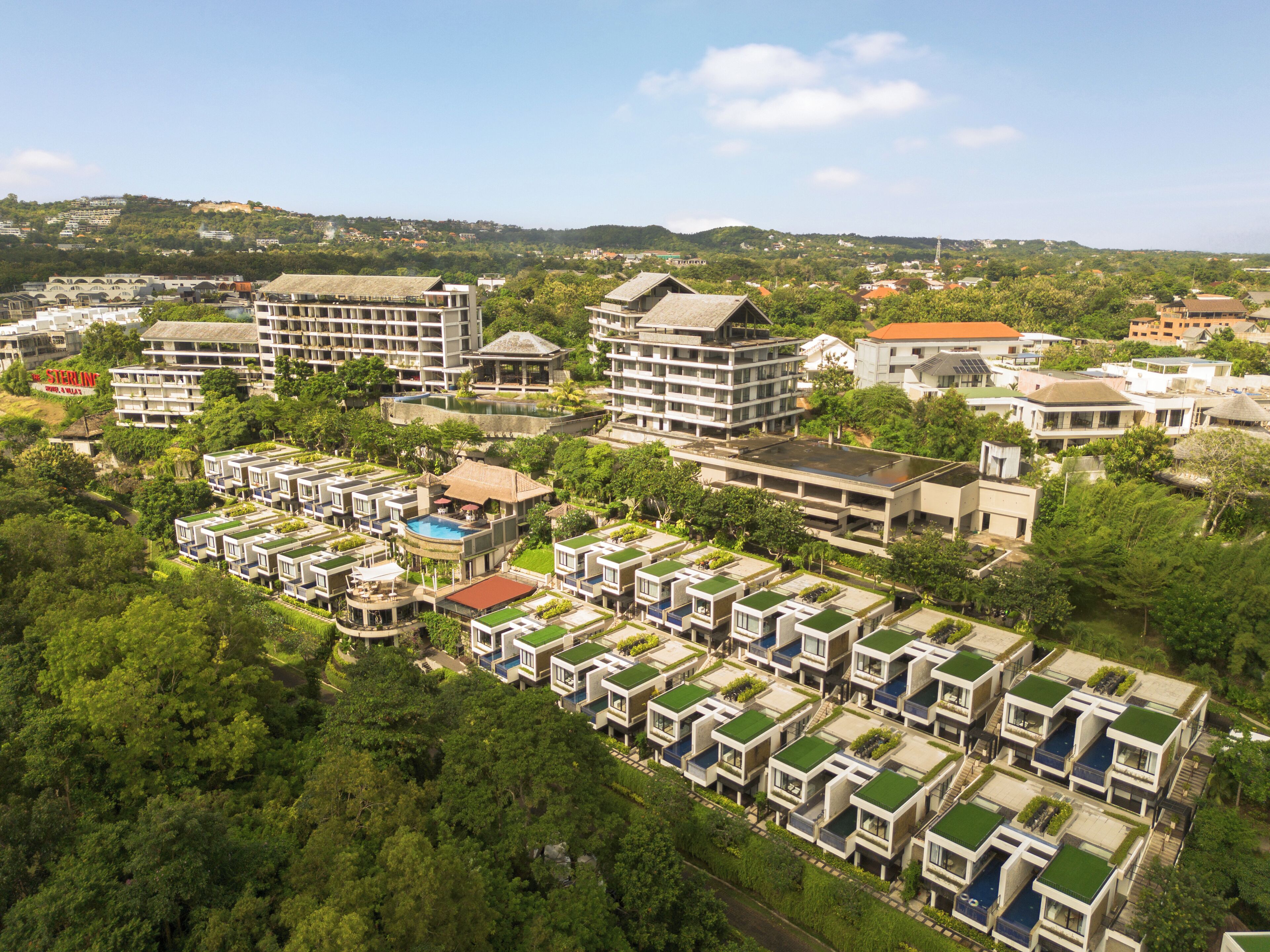 Un barrio residencial con casas modernas, una piscina y vistas de las colinas circundantes.