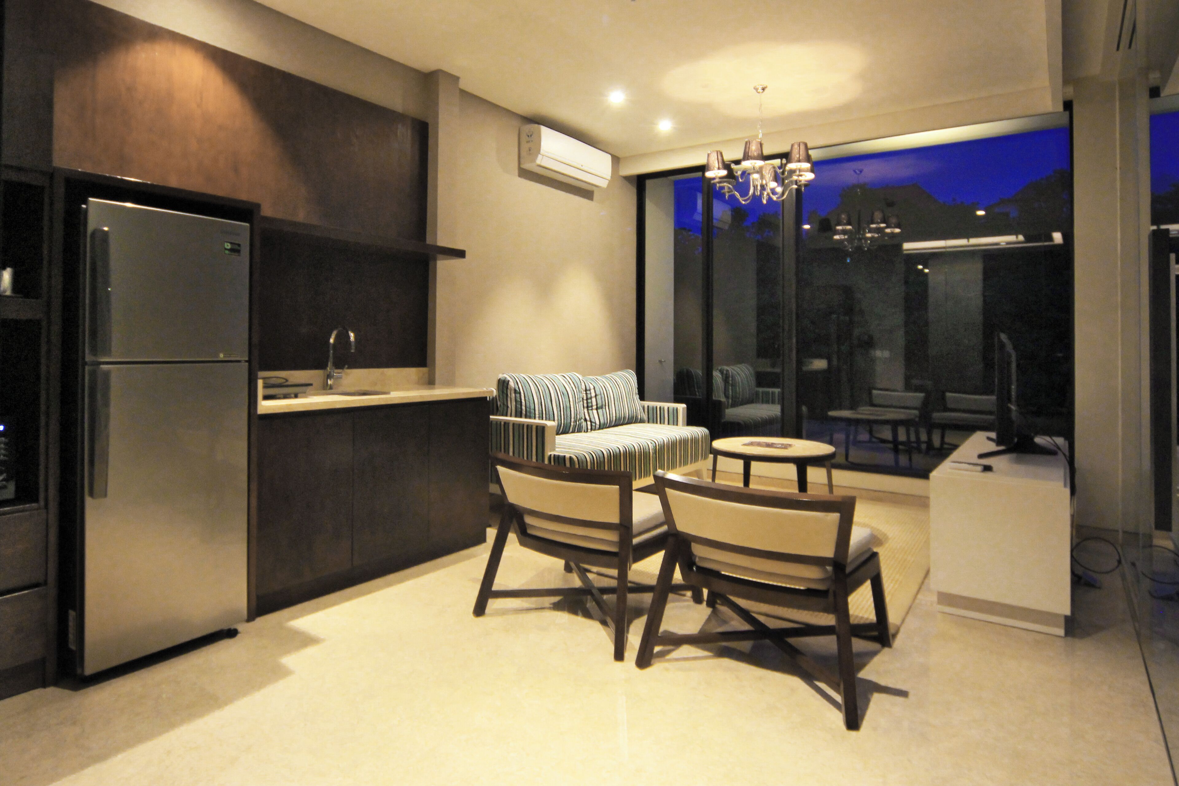 A modern kitchen with a built-in refrigerator, a dining area with two chairs and a small table, and a large window offering a view of the outdoors.
