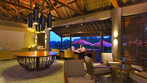 A spacious lounge area with a round table, comfortable seating, and a view of the outdoors. - The Sterling Villas (Pecatu)