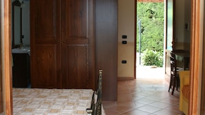 A bedroom with a bed, wooden wardrobe, and a bathroom visible through an open door.