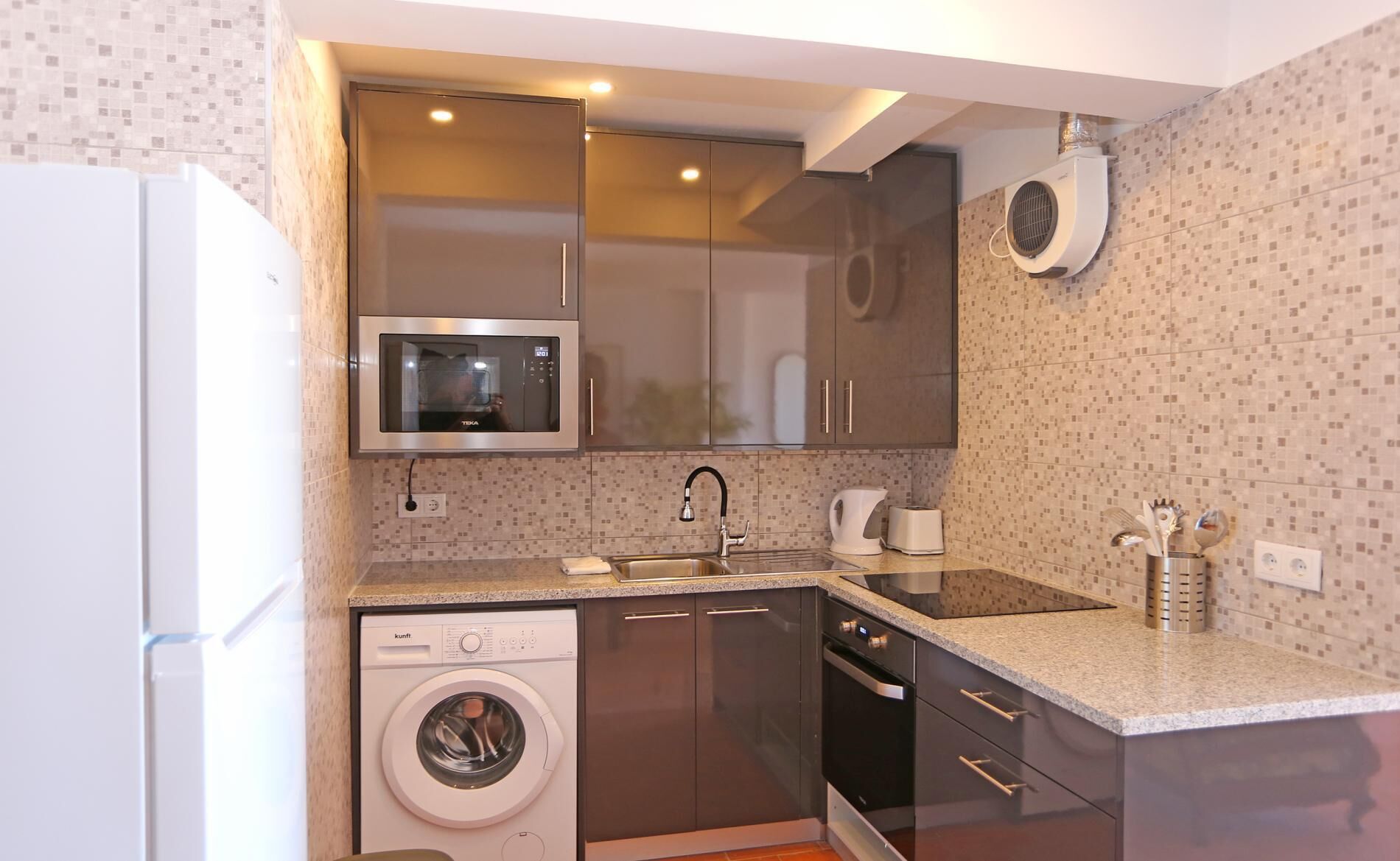 Cocina compacta equipada con microondas, horno, fregadero y lavadora.
